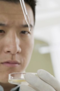 Close up of man with eye dropper and petri dish