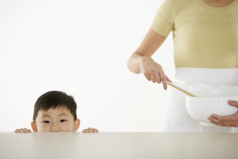 Boy watching mother with mixing bowl