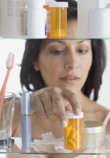 Young woman taking pills out of medicine cabinet