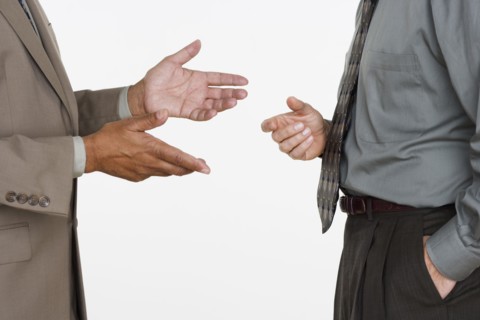 Mid section of two businessmen facing each other with hands gesturing