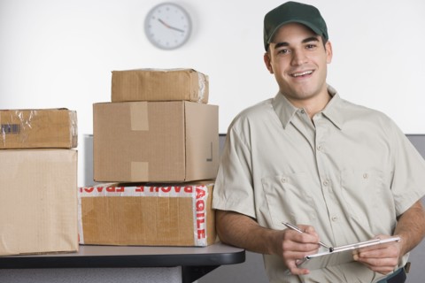 Portrait of delivery man with stack of boxes