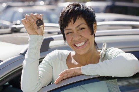 Portrait of woman holding car keys and standing with car door open