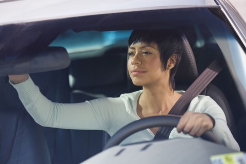 Woman adjusting rear view mirror in car