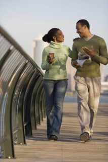 Couple walking across bridge with city behind them