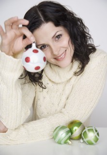 Portrait of woman holding up Christmas ornament