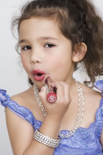 Portrait of girl applying makeup while playing dress up