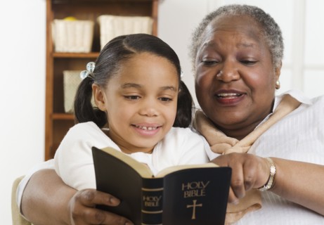 Senior woman reading the Bible to her granddaughter
