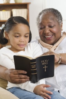 Senior woman reading the Bible to her granddaughter