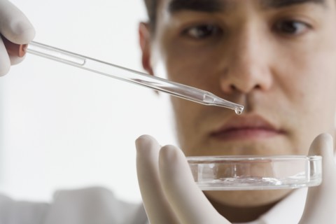 Scientist dropping chemicals into a Petri dish