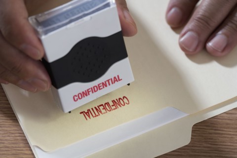 Close up of male hands using confidential stamp on file