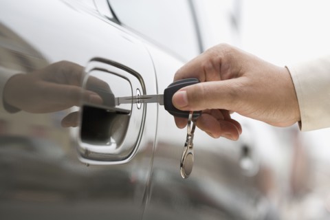 Close up of man's hand unlocking car door with key