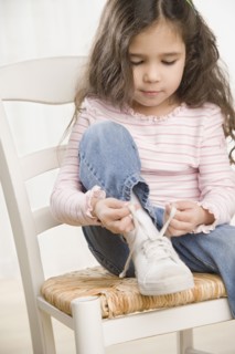 Young Hispanic girl tying shoe