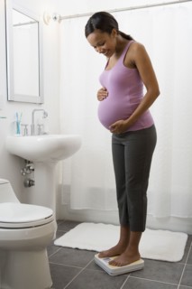 Pregnant African woman standing on scale