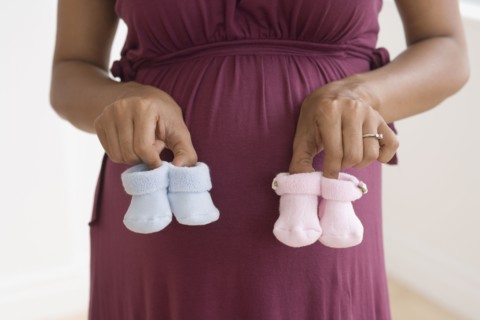 Pregnant African woman holding baby shoes