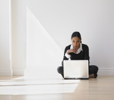 African businesswoman on floor looking at laptop