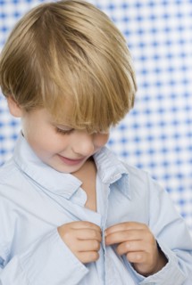 Young boy buttoning shirt