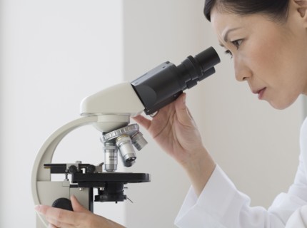 Asian female scientist looking into microscope