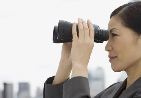 Profile of Asian businesswoman looking through binoculars