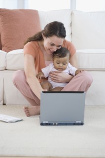 Hispanic mother using laptop with baby in lap