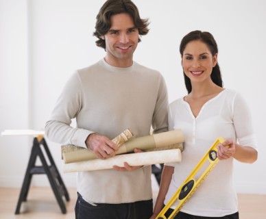 Hispanic couple holding rolls of wallpaper