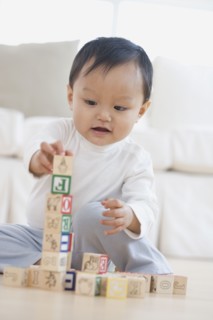 Asian baby playing with blocks on floor