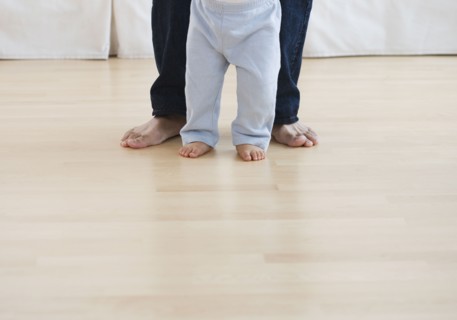 Low section of barefoot baby and father