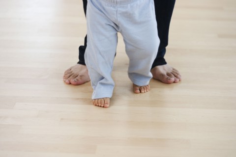 Low section of barefoot baby and father