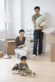 Asian parents watching baby play with blocks on floor