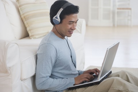 Asian man using laptop with headphones