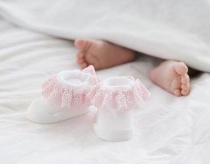 Baby booties next to newborn baby's feet