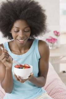 African woman eating bowl of fruit