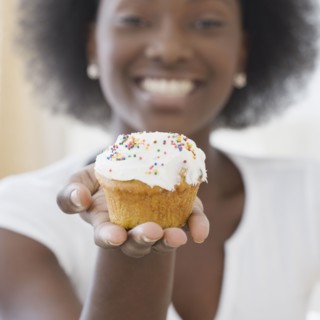 African woman holding cupcake