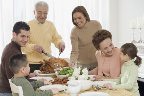 Multi-generational Hispanic family eating at Thanksgiving table