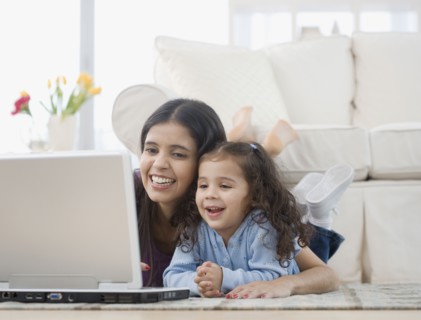 Hispanic mother and daughter looking at laptop