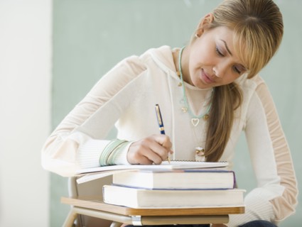 Young Hispanic woman writing at school desk