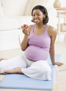 Pregnant African American woman eating apple