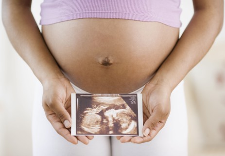 Pregnant African American woman holding ultrasound printout