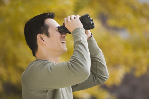 Asian man looking through binoculars