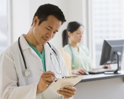 Asian male doctor writing on chart