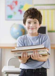 Hispanic boy holding stack of school books