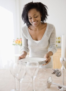 African woman carrying stack of plates