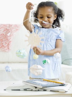 Mixed race girl making solar system mobile