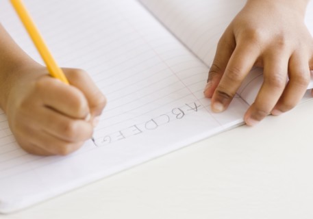 Mixed race girl writing ABC's