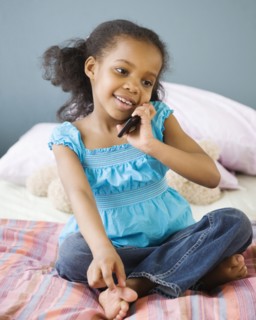Mixed race girl in bedroom using cell phone