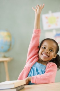 Mixed race girl raising hand to answer question