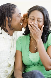 African man whispering in woman's ear