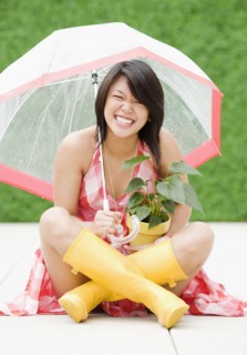 Asian woman sitting underneath umbrella in rain