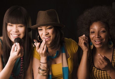 Multi-ethnic women putting on makeup