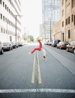 Hispanic teenage boy doing back flip in urban street