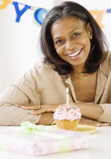 African woman smiling with birthday candle in cupcake